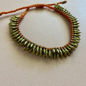 Adjustable stackable brass spike bracelet with orange cord.
